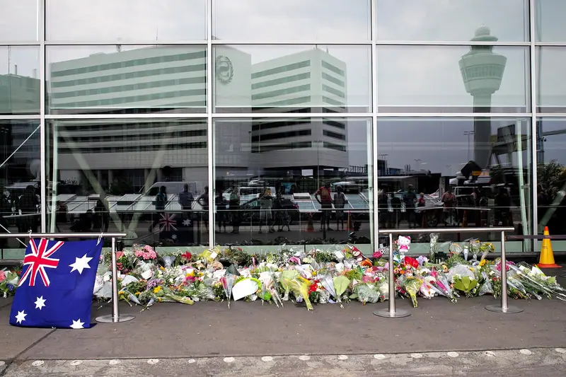 Flowers, notes and an Australian flag laid along the glass front of a terminal building at Amsterdam Schiphol Airport