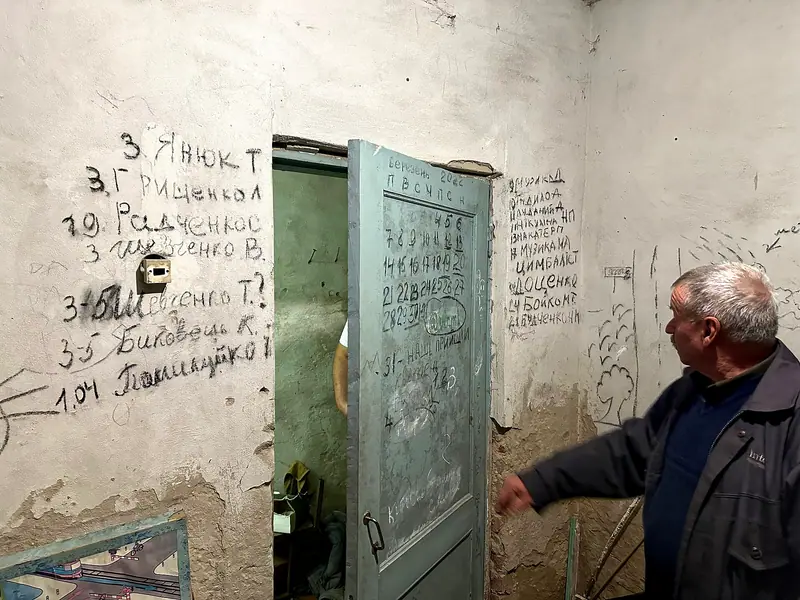 Handwritten calendar and lists of names on a wall of the school basement in Yahidne